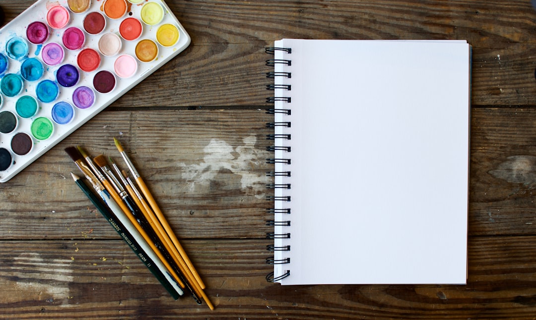 Photo by Tim Arterbury paint brushes next to drawing book and water color palette